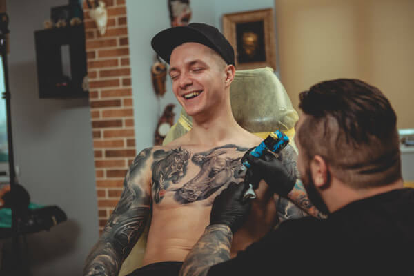 Homem tendo seu peito tatuado