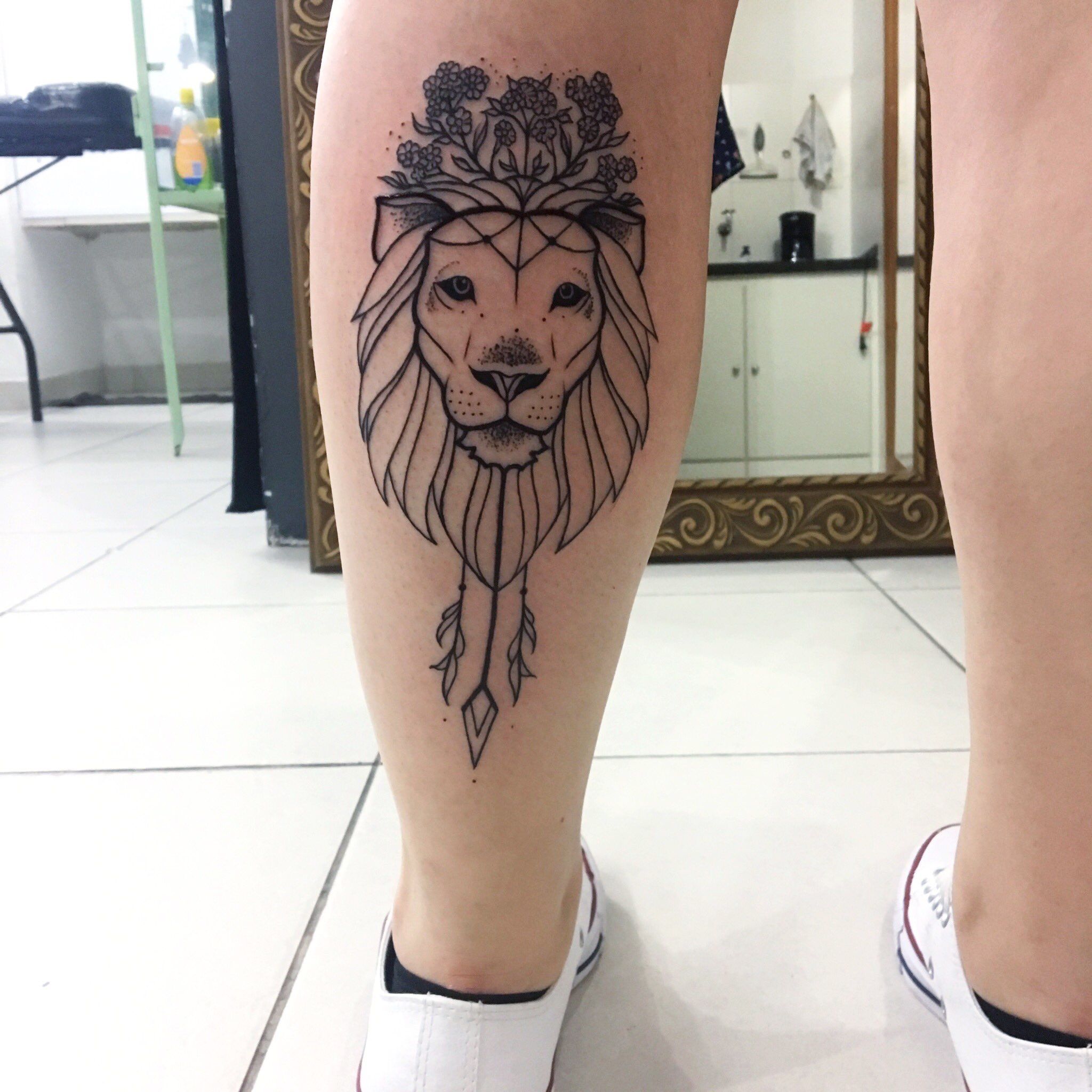 Tatuagem feminina de leão na panturrilha