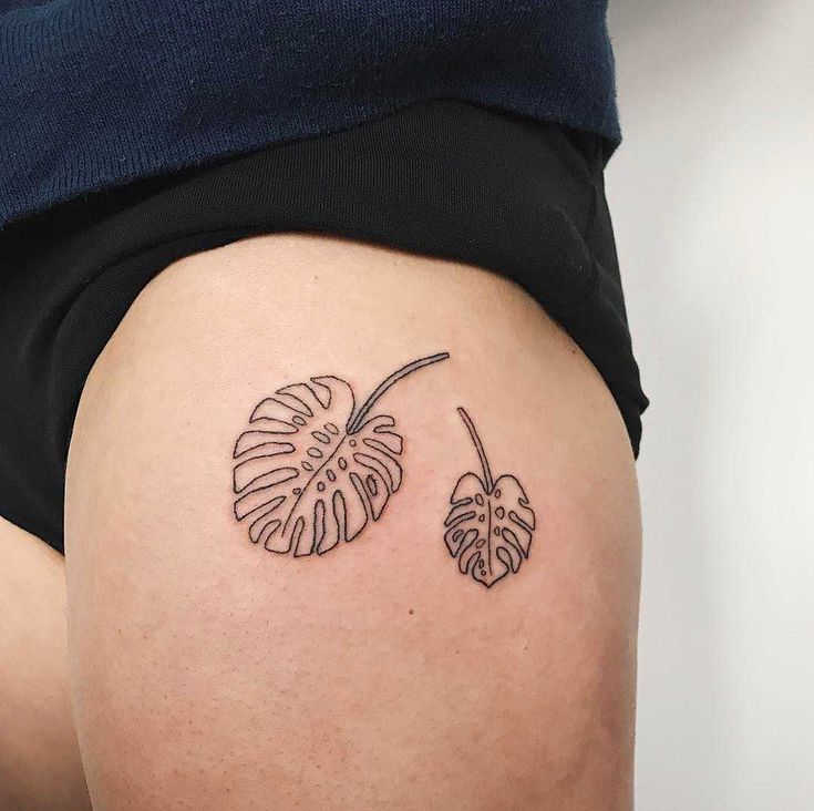 tatuagem feminina de folhas na coxa