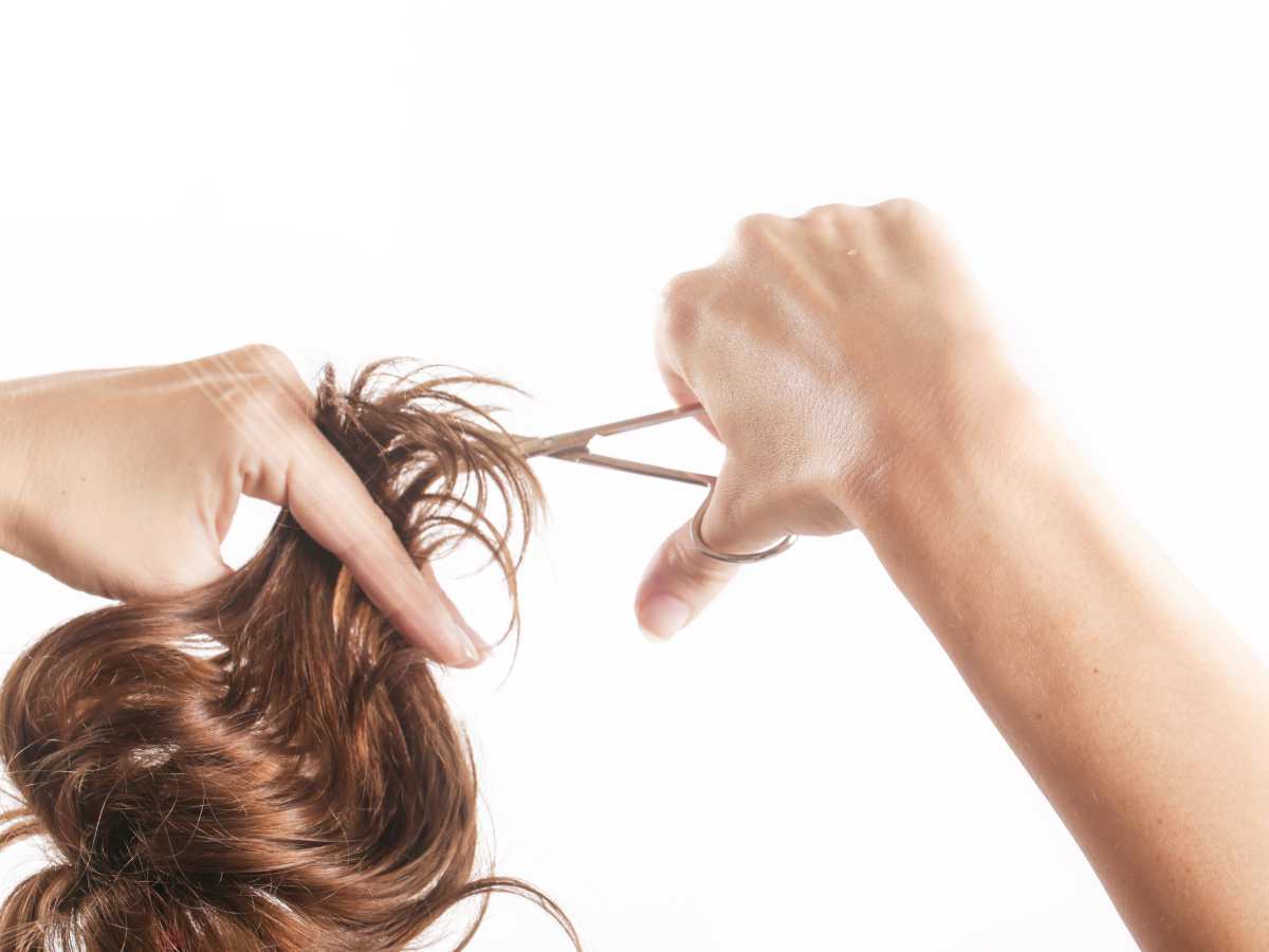 Corte de cabelo tendência. Foto aparece braços cortando fios de cabelo liso de cor castanho