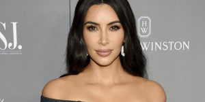 Estilos de Roupas que a Kim Kardashian usa. Foto mostra Kim Kardashian usando posando para foto com look escuro e maquiagem de olhos esfumados e lábios neutros.
