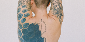 Tatuagens para cobrir outras. Foto mostra uma mulher de costas com as costas tatuadas de um desenho abstrato todo em preto.
