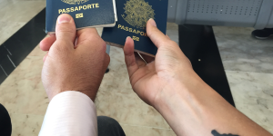 Tatuagens para quem ama viajar. Foto aparece dois braços segurando passaportes e um dos braços tatuado com um avião.