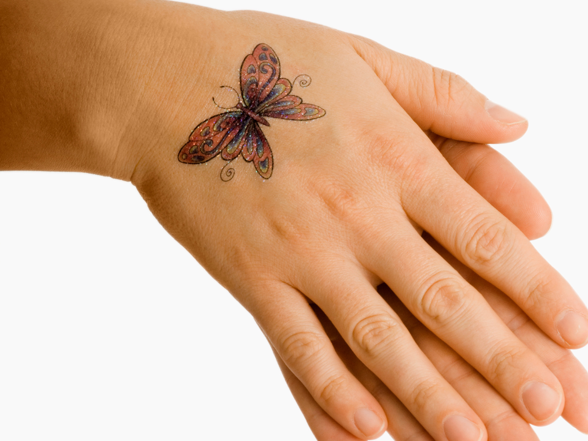 Tatuagens delicadas para mulheres com 50 anos. Foto aparece uma mão com uma tatuagem de borboleta vermelha