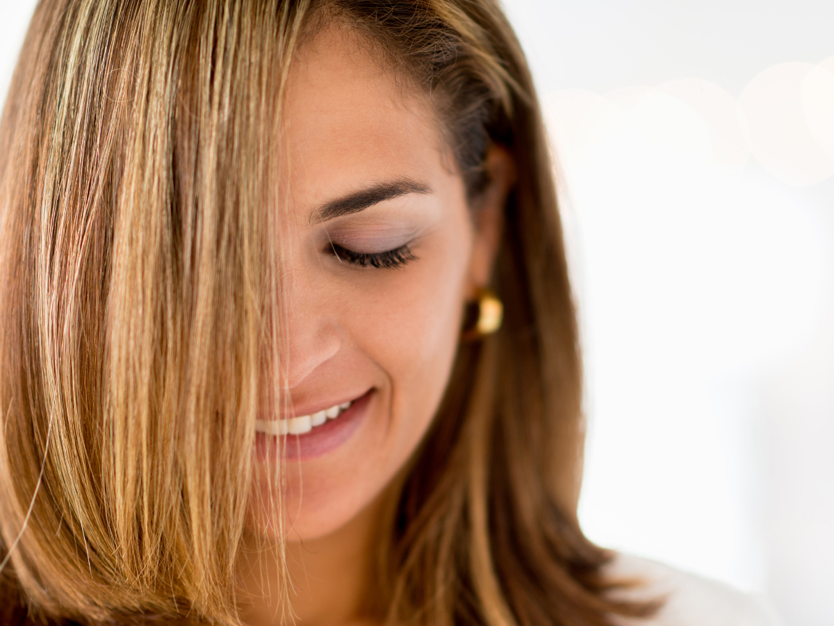 Alisar o cabelo sem chapinha. Foto mostra uma mulher de cabelos castanhos claros lisos e sorrindo