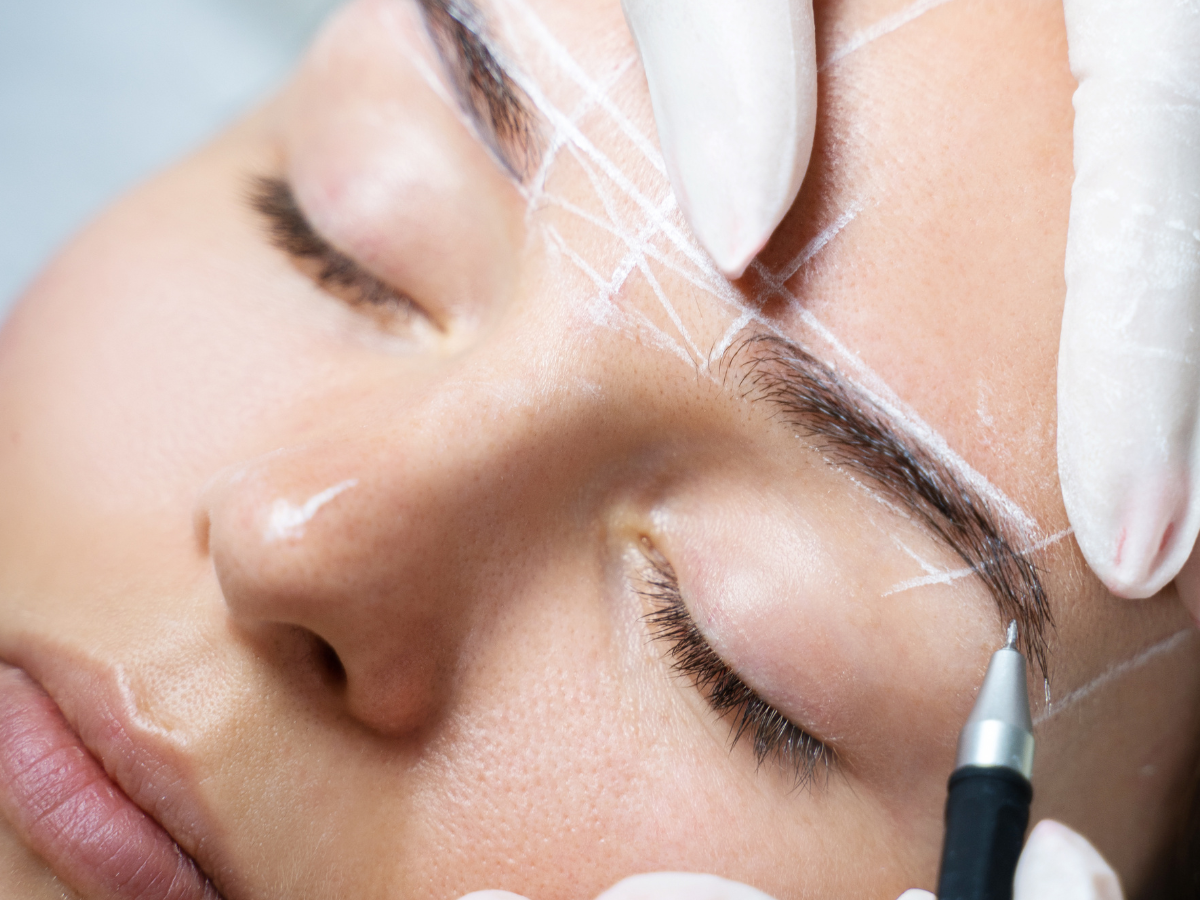 Risco na sobrancelha. Foto mostra uma mulher com o rosto riscado de branco e fazendo um procedimento na sobrancelha.