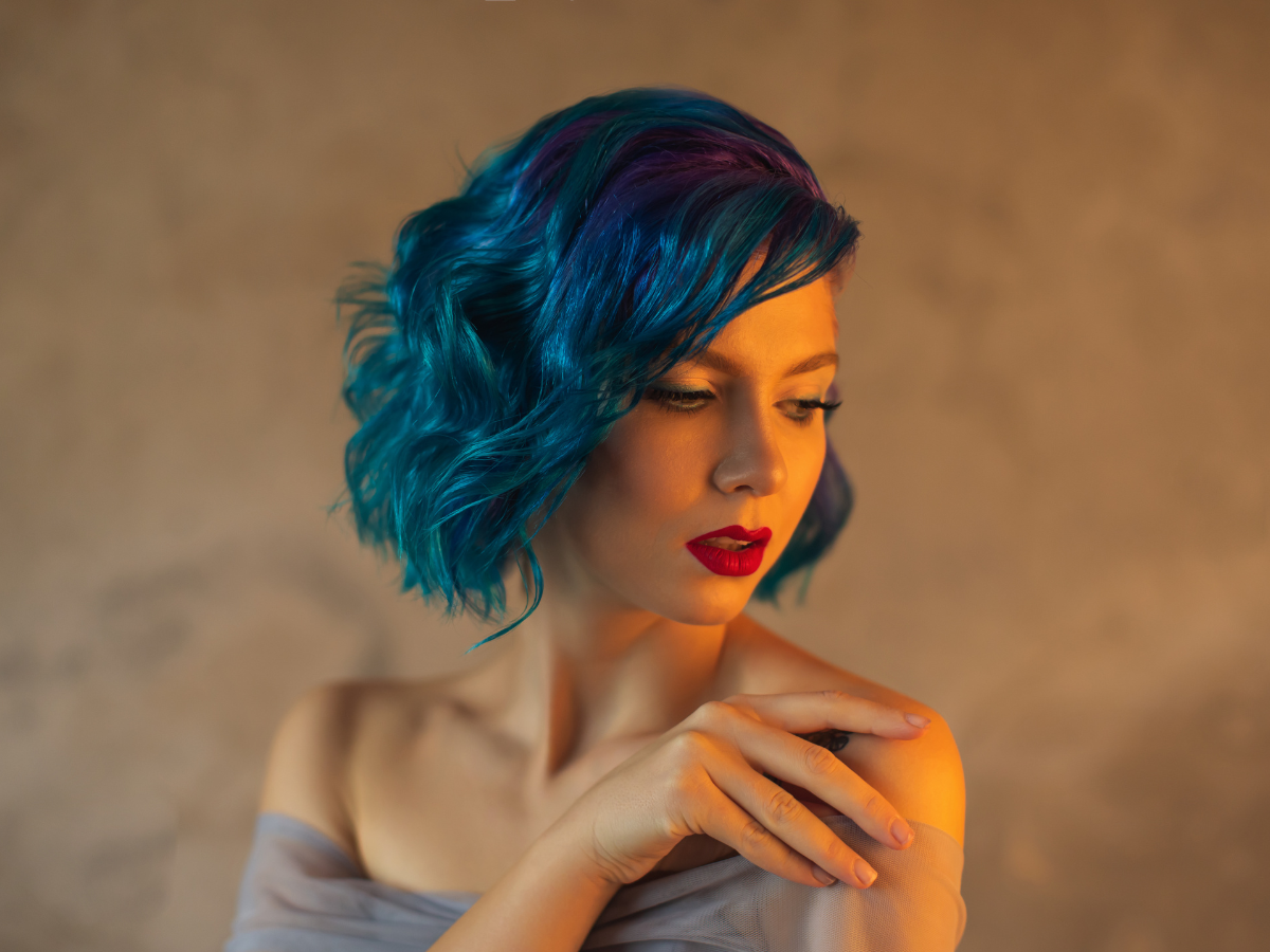 Cores de cabelo ousadas. Foto mostra uma mulher branca com cabelos azuis.