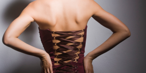 Motivos para não usar espartilho. Foto mostra mulher de costas usando espartilho de cor vinho