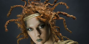 Penteados para o Halloween 2023. Foto mostra cabelo laranja desarrumado com tiara com cobras para representar a medusa
