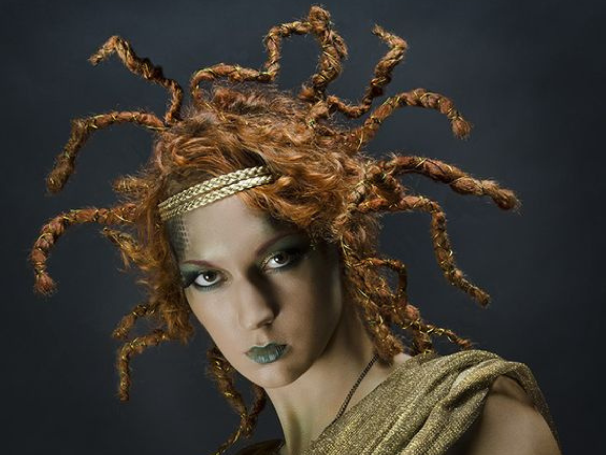 Penteados para o Halloween 2023. Foto mostra cabelo laranja desarrumado com tiara com cobras para representar a medusa 