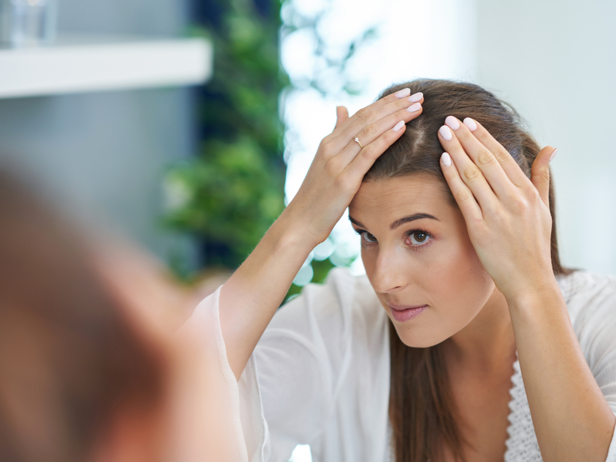 Scalp Care. Foto traz uma mulher em frente ao espelho olhando o couro cabeludo.