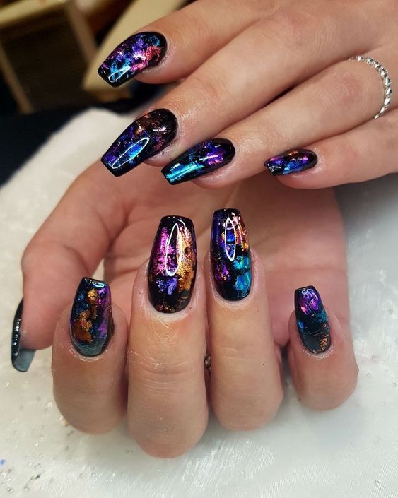 Nail arts deslumbrantes.. Foto traz unhas com retalhos metalicos coloridos e esmalte na cor preta.
