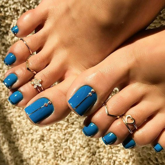 unhas decoradas nos pés no verão. Foto traz unhas azuis com pedrarias