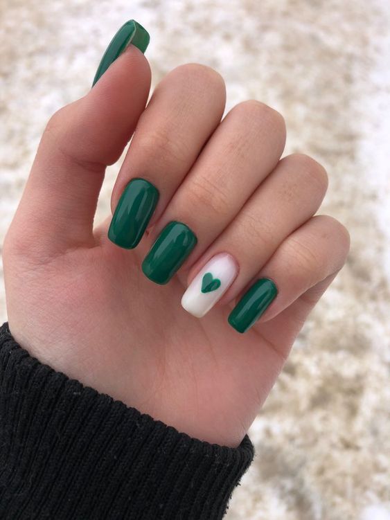 unhas delicadas elegantes de cor verde e com dedo anelar decorado com branco e um coração verde