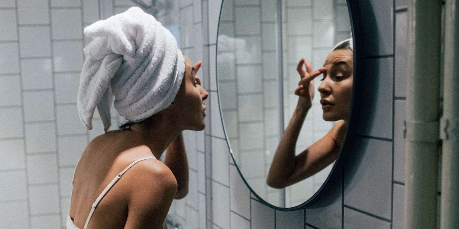 mulher cuidando de seu rosto em frente a espelho