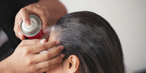 pessoa aplicando spray em cabelo