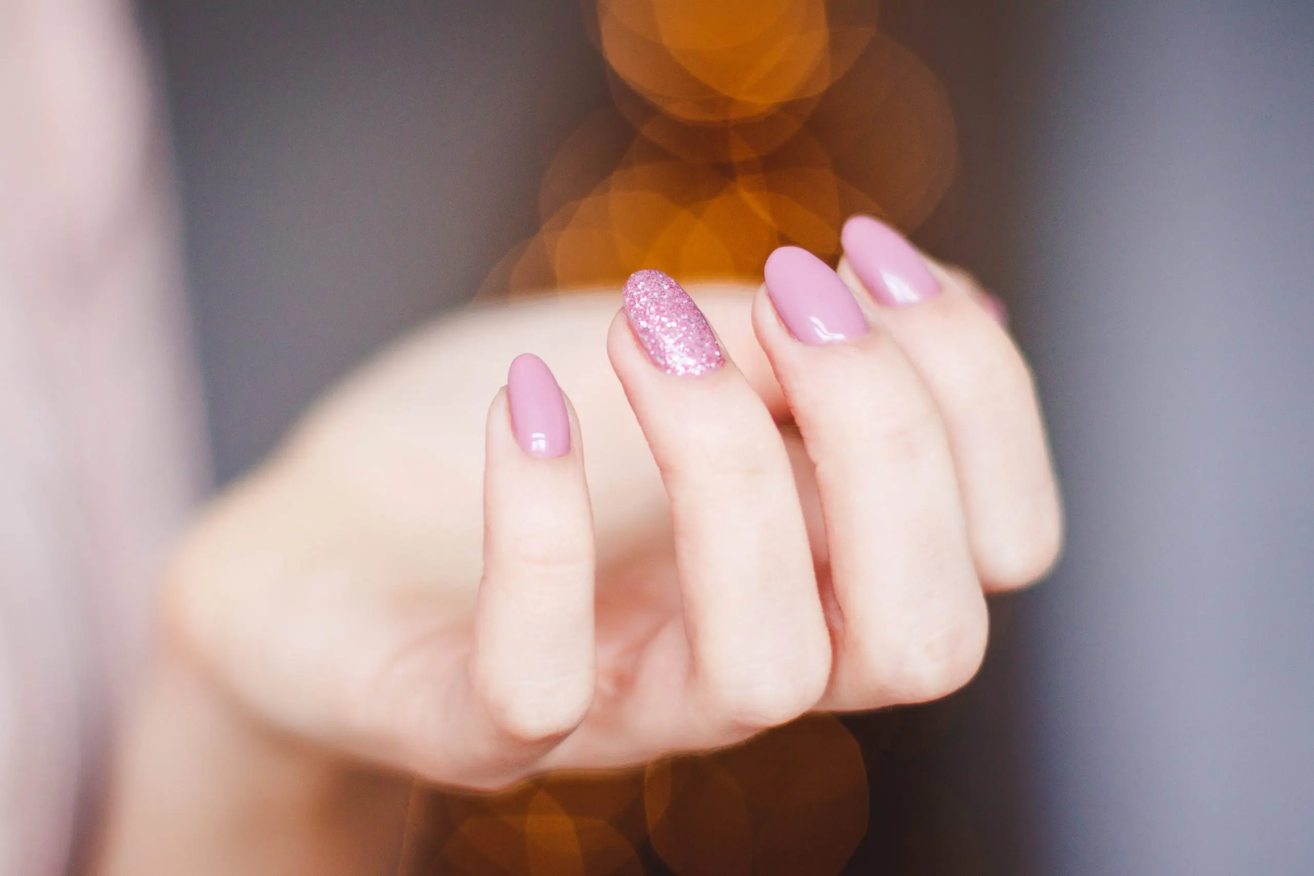 mão com unhas pintadas de cor-de-rosa